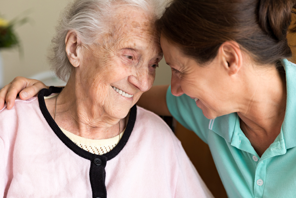 Medical professional and elderly patient embracing each other