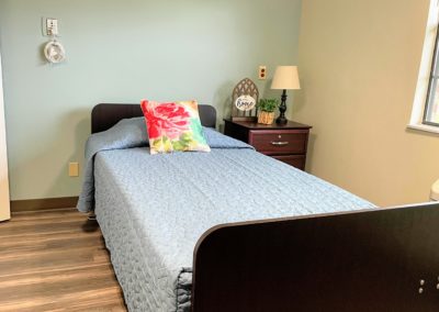 Newly renovated resident room with twin sized bed and side table