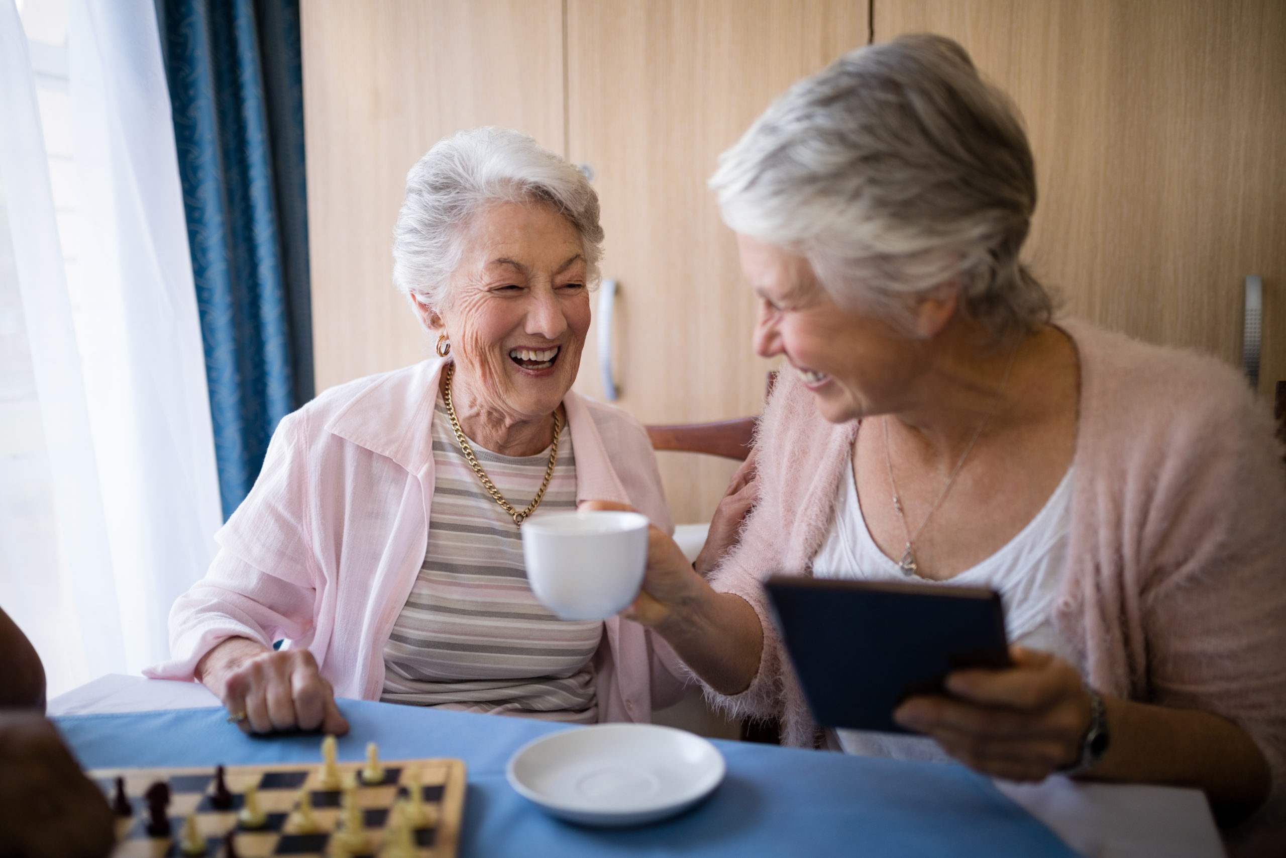 Happy,Senior,Friends,Talking,While,Having,Coffee,And,Playing,Chess